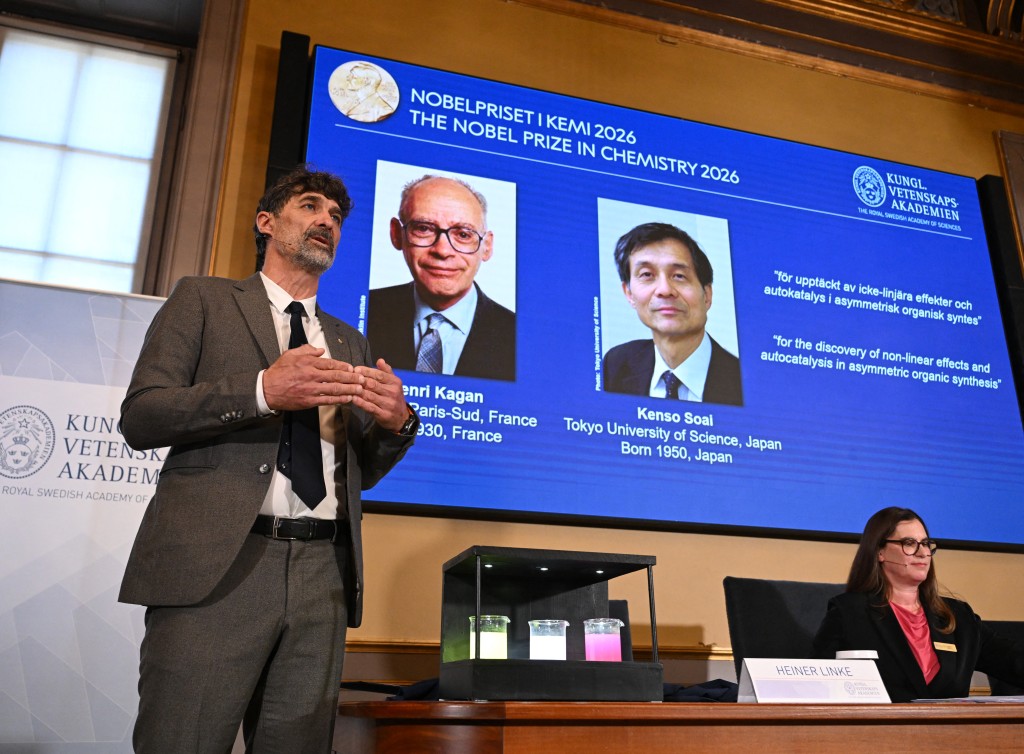 The chair of the Nobel Committee for Chemistry Heiner Linke (L) explains the field of research of Nobel Prize winners France's Henri Kagan and Japan's Kenso Soai (displayed on the screen in the background) during a press conference to announce the winners of the 2026 Nobel Prize in Chemistry at the Royal Swedish Academy of Sciences in Stockholm, Sweden, on October 7, 2026. (AFP)
