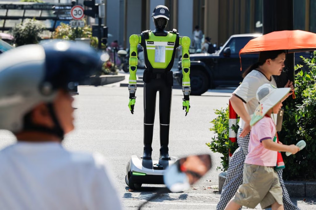 People walk past a humanoid robot traffic police officer developed by SUPCON while it stands on duty on a street in Hangzhou, Zhejiang province, China, July 31, 2026. REUTERS/Go Nakamura 