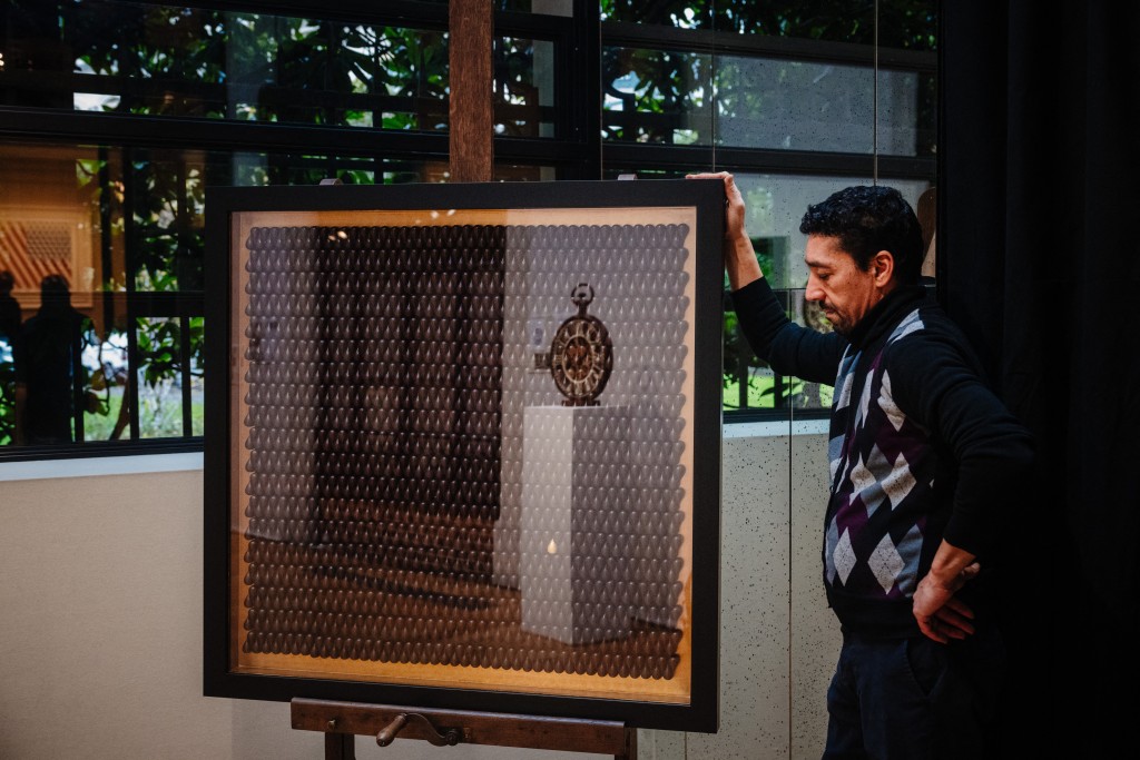 An employee stands by a chocolate pastry made by France's pastry chef Jerome de Oliveira displayed on November 28, 2025 in Paris three days ahead of an auction of 25 grands chefs pastries for the benefit of the BAB Charity association, which works for the well-being and development of children with leukaemia who are hospitalised at the Armand Trousseau Hospital in Paris. (Photo by Dimitar DILKOFF / AFP)