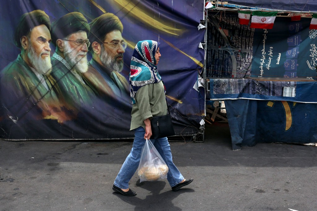 Photo by - / AFP An Iranian woman walks past a billboard bearing the images of the late founder of the Islamic Revolution supreme leader Ayatollah Ruhollah Khomeini (L), the late Iranian supreme leader Ali Khamenei assassinated in February 2026, and his son, the current supreme leader Mojtaba Khamenei (R), erected along a street in Tehran on May 28, 2026.