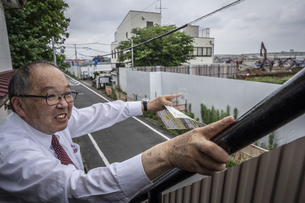 Photo by YUICHI YAMAZAKI / AFP  This picture taken on June 30, 2026 shows Yasuo Yamazaki, a representative of a citizens' group expressing concerns about the construction of a data centre, speaking while pointing toward the site of the project in Hino, Tokyo prefecture.