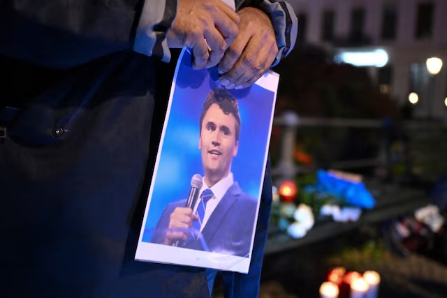 A man holds a picture of Charlie Kirk during a vigil under the line "In Memory of Charlie Kirk, for freedom, patriotism and justice" in front of the Embassy of the United States after U.S. right-wing activist, commentator, Charlie Kirk, an ally of U.S. President Donald Trump, was shot dead during an event at Utah Valley University, Orem, U.S., in Berlin, Germany September 11, 2025. REUTERS/Annegret Hilse