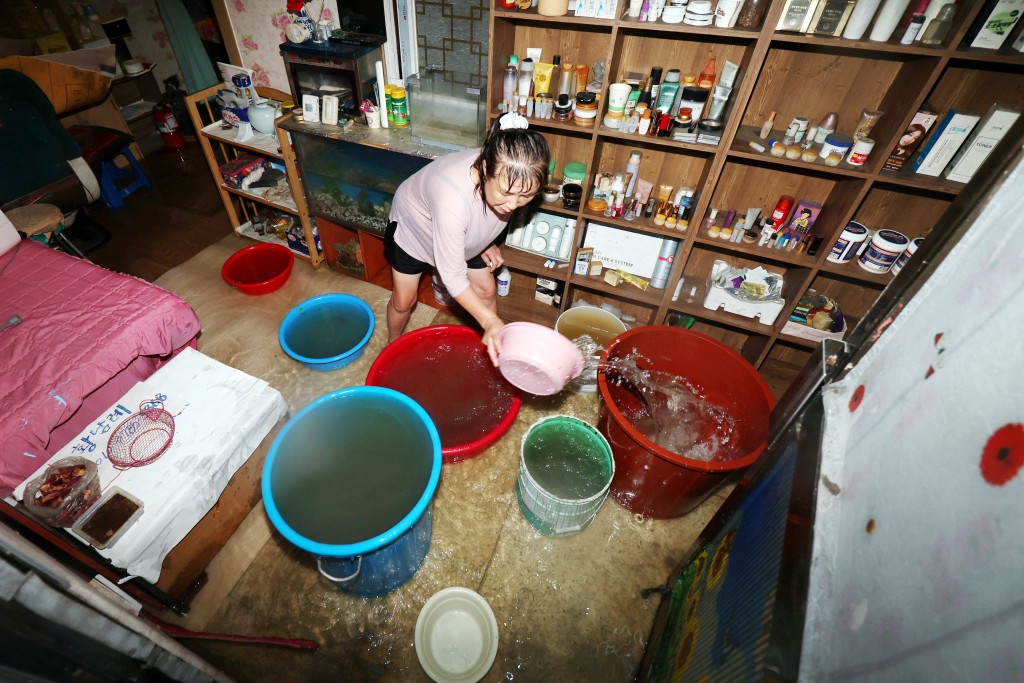 A woman cleans the flooded floor of her hair salon, caused by torrential rain in Gwangju, South Korea, July 17, 2025. (Reuters)