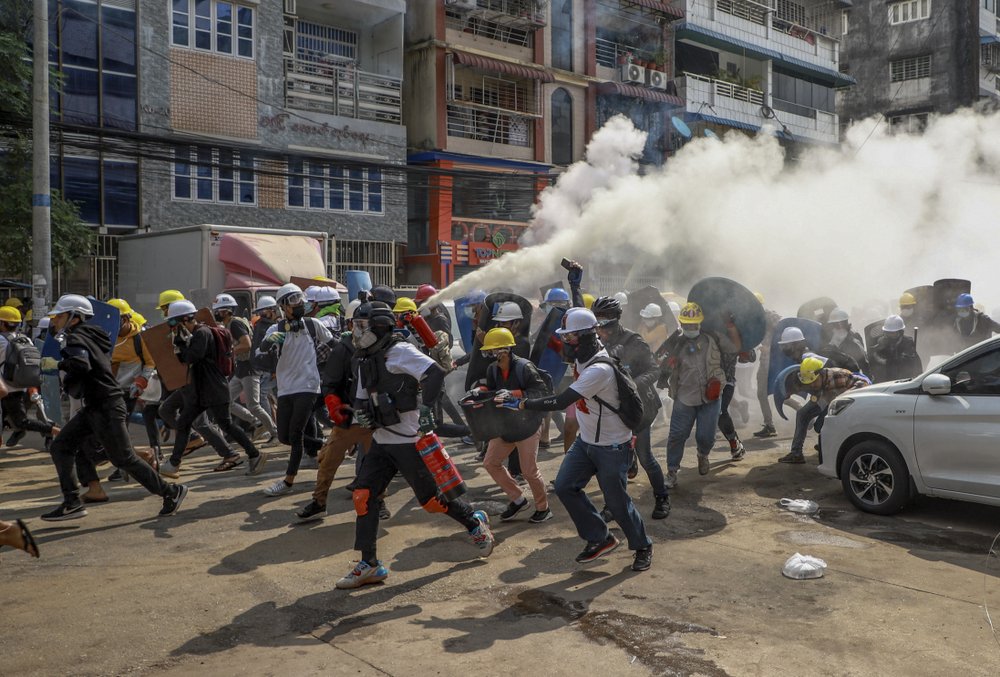 Anti-coup protesters run as one of them discharges a fire extinguisher to counter the impact of tear gas fired by riot policemen in Yangon, Myanmar, Wednesday, March 3, 2021