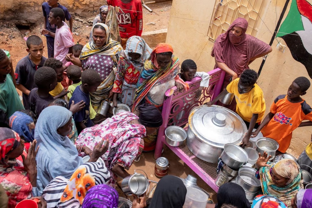 Sudanese women from community kitchens run by local volunteers distribute meals for people who are affected by conflict and extreme hunger and are out of reach of international aid efforts, in Omdurman, Sudan, July 27, 2024. REUTERS/Mazin Alrasheed/File Photo