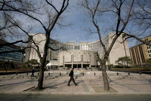 People walk past the headquarters of the central bank of the People's Republic of China in Beijing February 16, 2009. REUTERS/Jason Lee/File Photo
