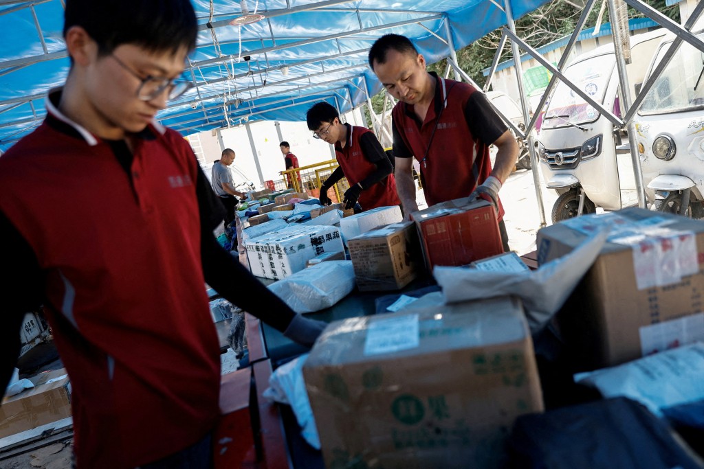 Delivery workers sort packages on a conveyor belt amid the "618" shopping festival, at a logistics station in Beijing, China June 12, 2023. REUTERS/Tingshu Wang