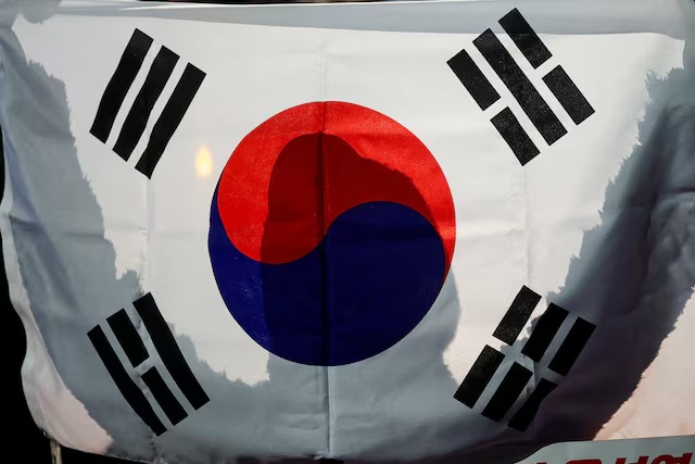 A person holds a South Korean flag in front of the National Assembly in Seoul, South Korea, December 6, 2024. REUTERS/Kim Hong-ji/File photo