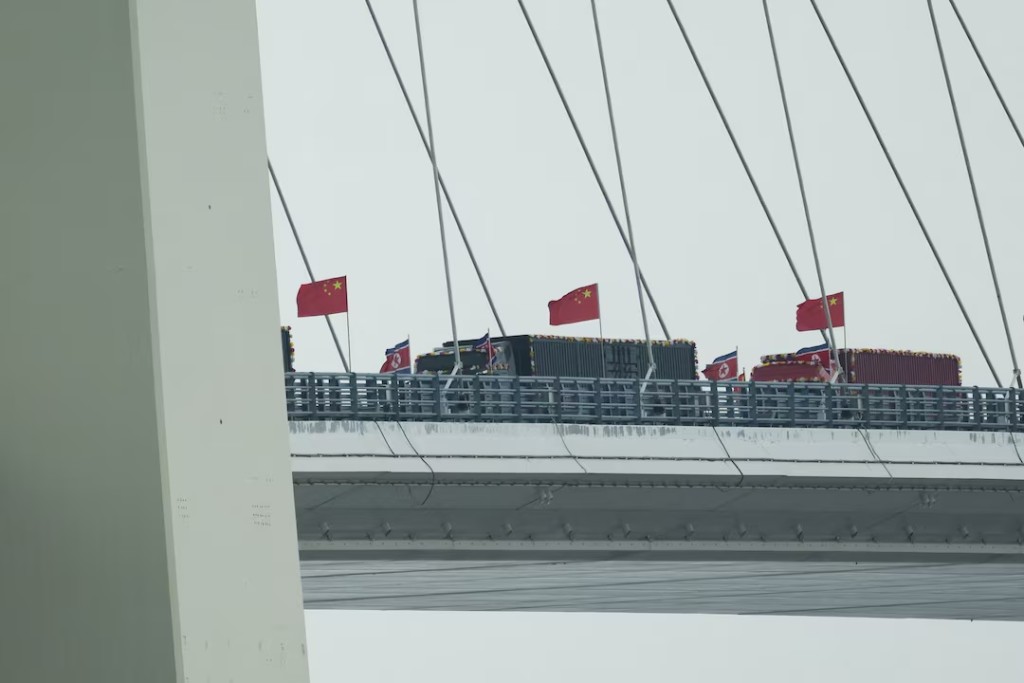 Trucks adorned with North Korean flags enter the Chinese side of the newly opened New Yalu River Bridge, which connects North Korea's Sinuiju with China's Dandong New Zone, in Dandong, Liaoning province, China, October 15, 2026. REUTERS/Florence Lo