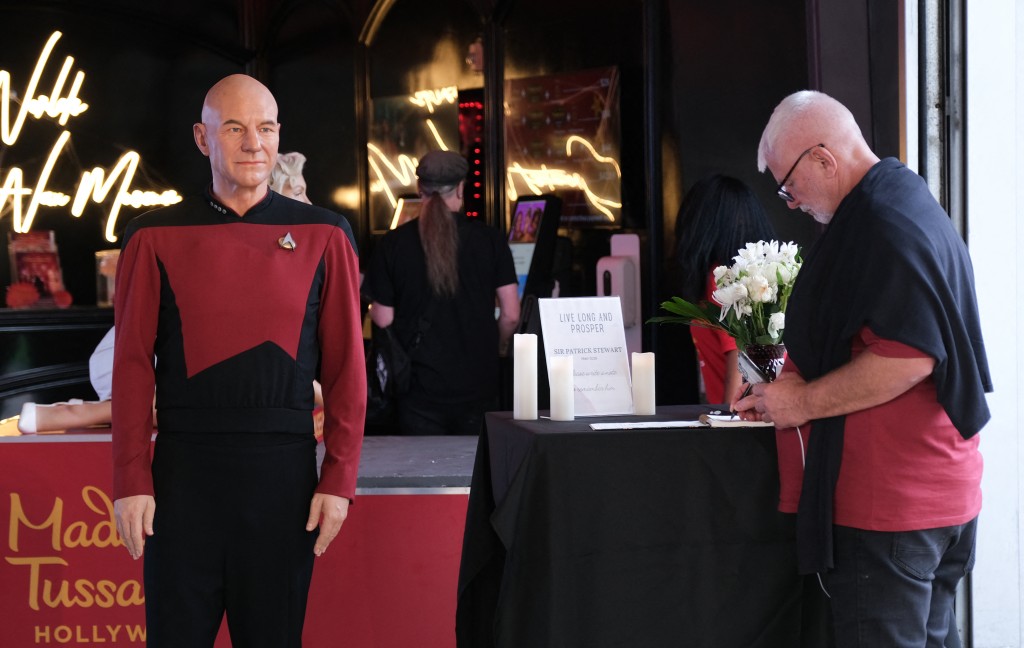 Photo by CHRIS DELMAS / AFP  A visitor signs a message of remembrance next to a wax figure of Sir Patrick Stewart at Madame Tussauds museum following the announcement of his death, in Hollywood, California, on October 29, 2026.