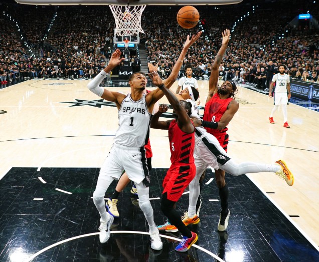 Victor Wembanyama, left, reaches for a rebound over the Trail Blazers' Jrue Holiday and Jerami Grant, right. REUTERS