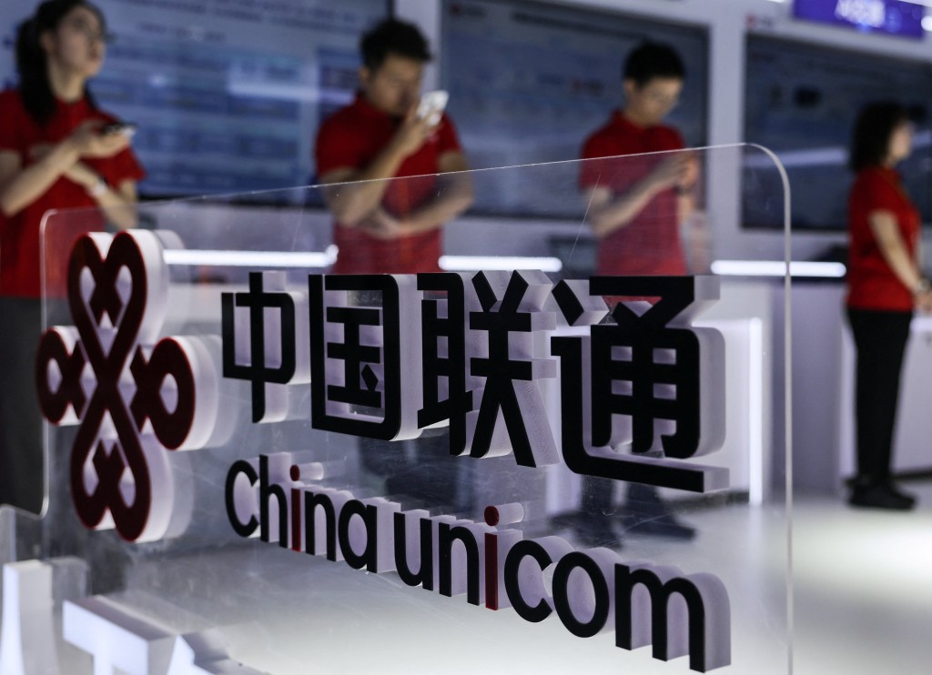 Young people wearing red T-shirts use their smartphones next to China Unicom's logo at its booth at China International Fair for Trade in Services (CIFTIS) in Beijing, China, September 10, 2025. REUTERS/Maxim Shemetov