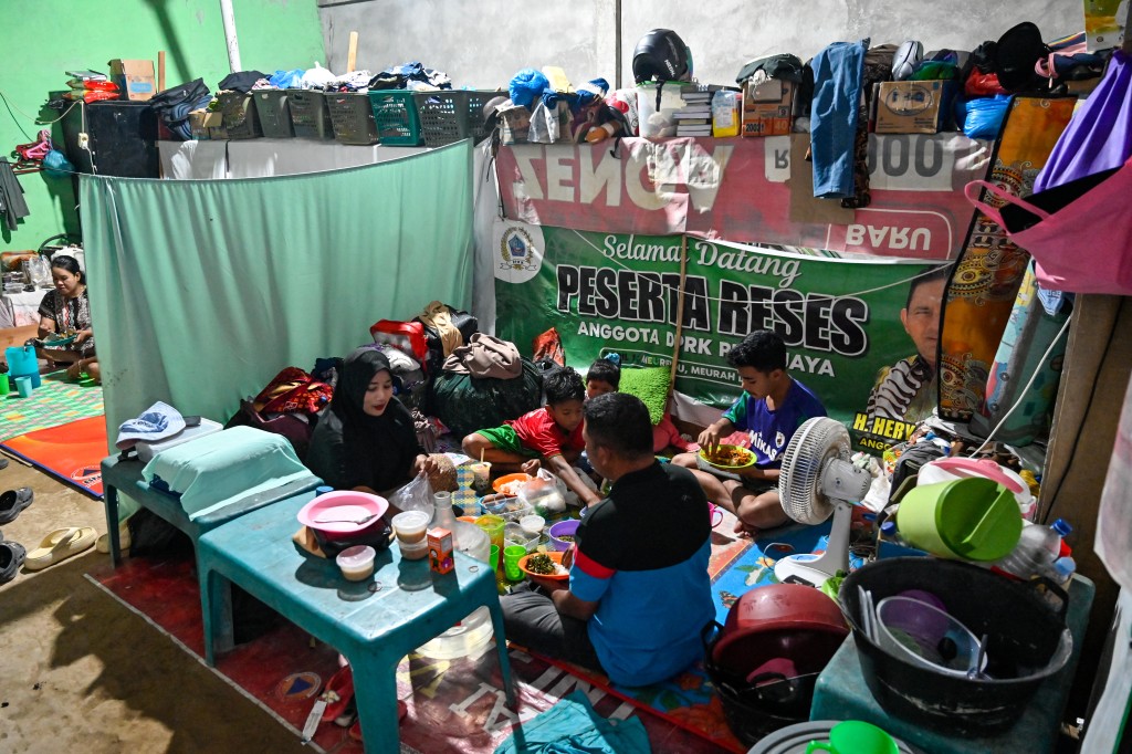 Photo by CHAIDEER MAHYUDDIN / AFP  A family breaks their day's Ramadan fast in a temporary shelter for flood survivors in Meurah Dua, Aceh province's Pidie Jaya district on February 21, 2026, after devastating floods and landslides struck Indonesia's Sumatra late last year.