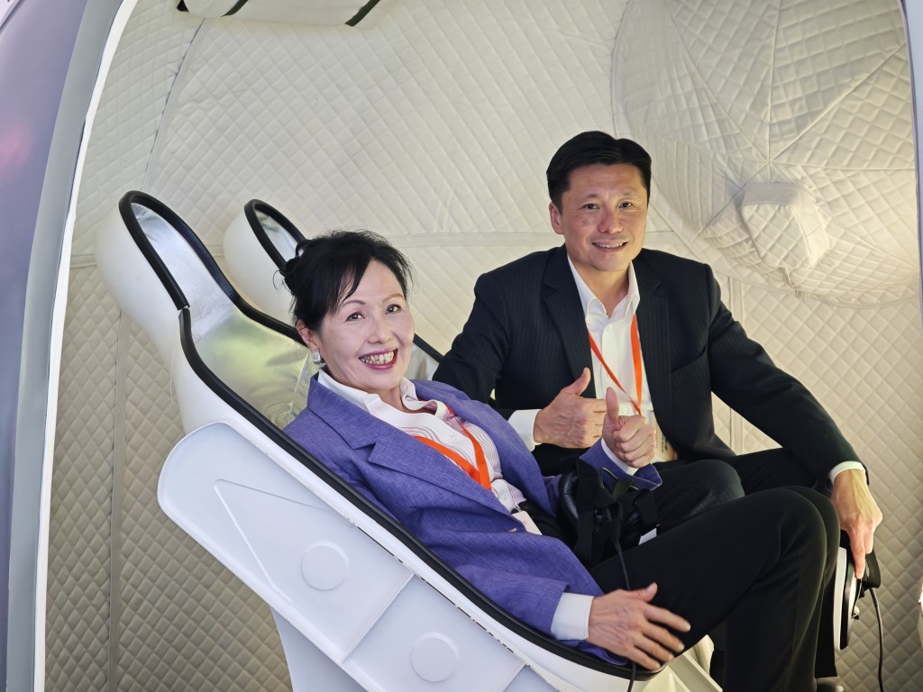 Convenor of the Working Group on Patriotic Education Eliza Chan Ching-har (left) and Director of Information Services John Tse Chun-chung (right) try out a simulated return capsule for a taste of the astronaut experience. Convenor of the Working Group on Patriotic Education Eliza Chan Ching-har (left) and Director of Information Services John Tse Chun-chung (right) try out a simulated return capsule for a taste of the astronaut experience.
