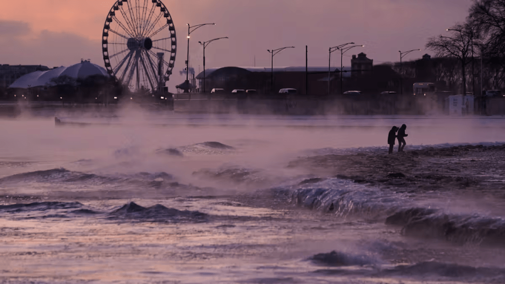 People walk on an ice covered beach along the shore of Lake Michigan, Friday, Jan. 23, 2026, in Chicago. (AP Photo/Kiichiro Sato)