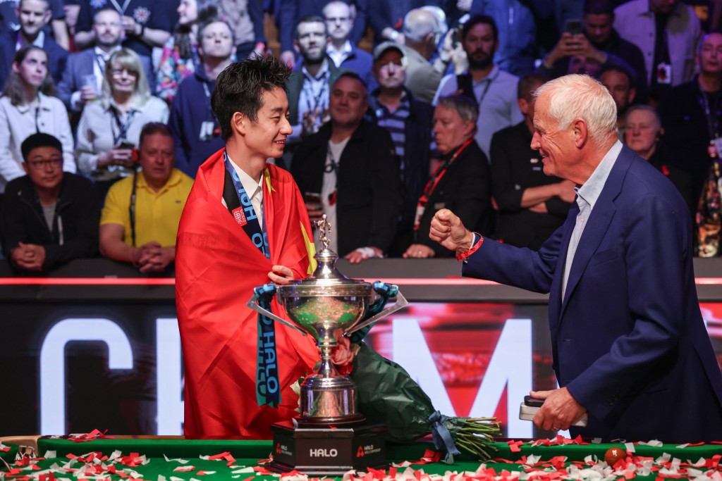 China's Wu Yize (L) is congratulated by English sporting promotor Harry Hearn (R) during the awards ceremony after his victory over England's Shaun Murphy in the World Snooker Championship final round at The Crucible in Sheffield, northern England on May 4, 2026. (Photo by Darren Staples / AFP)