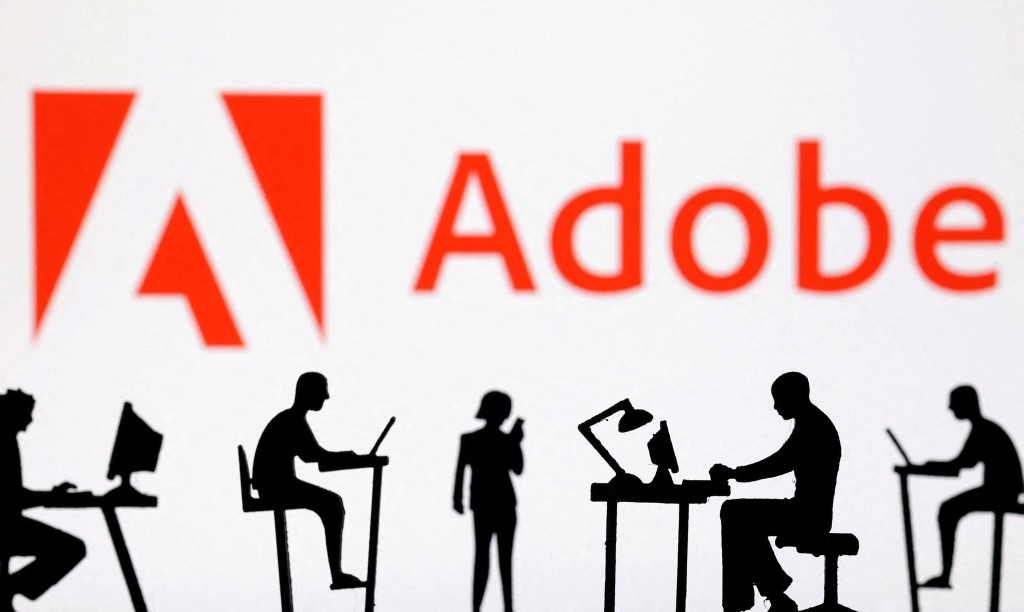 igurines with computers and smartphones are seen in front of Adobe logo in this illustration taken, February 19, 2024. REUTERS
