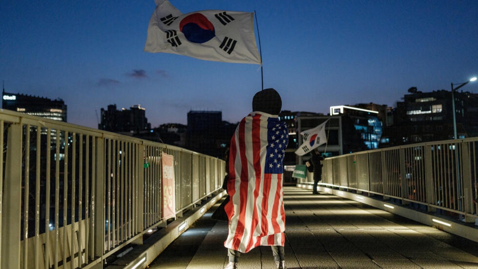 A supporter of impeached President Yoon Suk Yeol draped in a US flag waves South Korea's in the capital Seoul © Yasuyoshi CHIBA / AFP A supporter of impeached President Yoon Suk Yeol draped in a US flag waves South Korea's in the capital Seoul © Yasuyoshi CHIBA / AFP