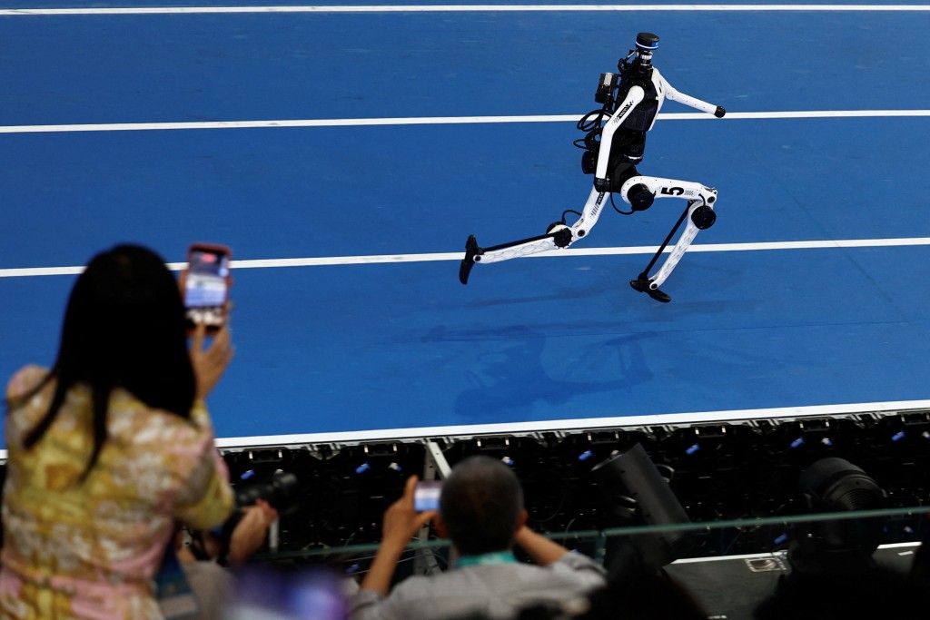Spectators use smartphones as they watch a Tiangong humanoid robot compete. (Reuters)