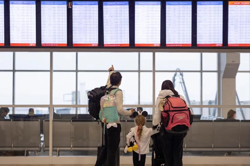 People check the flight tracker screens at the Dallas Fort Worth International Airport in Fort Worth, Texas, U.S., January 23, 2026. REUTERS/Alyssa Pointer