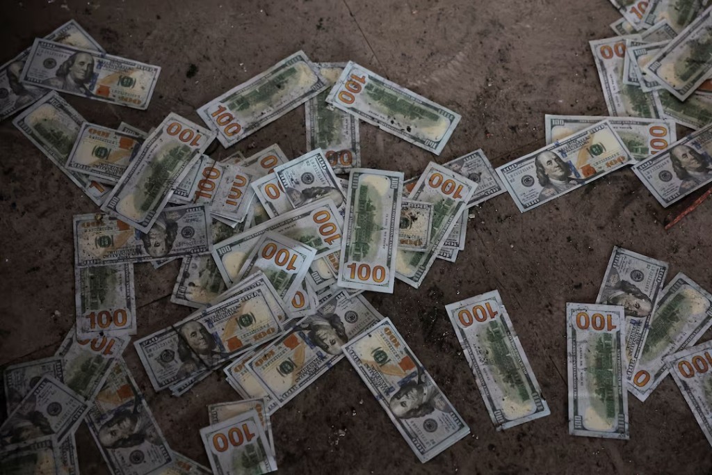 Counterfeit U.S. 100 dollar banknotes on the floor inside a compound in O'Smach used for scam operations, at the Chong Chom-O'Smach border crossing, which was bombed and occupied by the Thai military in December following clashes between Thailand and Cambodia along a disputed border area, in Samraong, Oddar Meanchey province, Cambodia, February 2, 2026. REUTERS/Chalinee Thirasupa