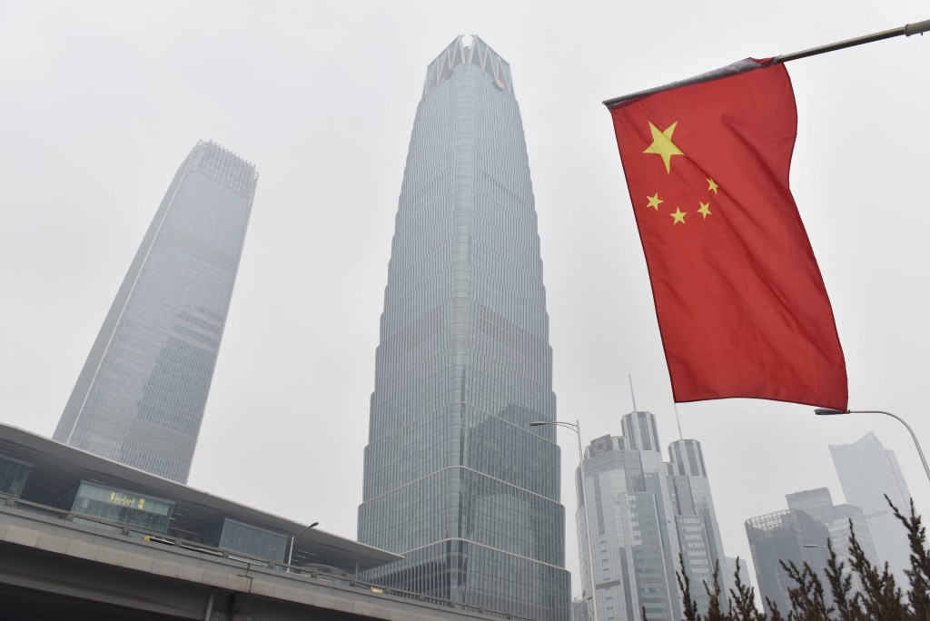 A Chinese flag flies near buildings in the central business district on a polluted day in Beijing on February 27, 2018.  Photo by GREG BAKER / AFP