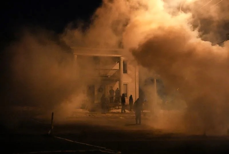 Members the community stand outside a building amidst tear gas used by law enforcement, as tensions rise after federal law enforcement agents were involved in a shooting incident, a week after a U.S. Immigration and Customs Enforcement (ICE) agent fatally shot Renee Nicole Good, in north Minneapolis, Minnesota, U.S., January 14, 2026. REUTERS/Leah Millis