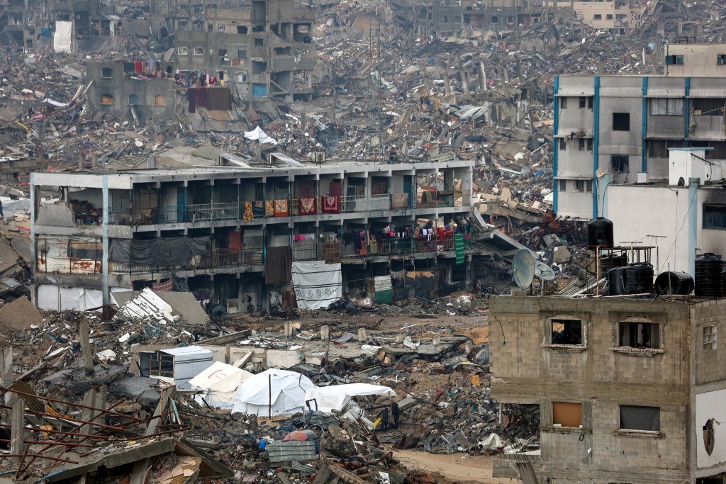 Photo by OMAR AL-QATTAA / AFP. People camp in a heavily damaged UN school surrounded by destruction, as displaced Palestinians return to the northern areas of the Gaza Strip, in Jabalia, on January 23, 2025, during a ceasefire in the war between Israel and Hamas.