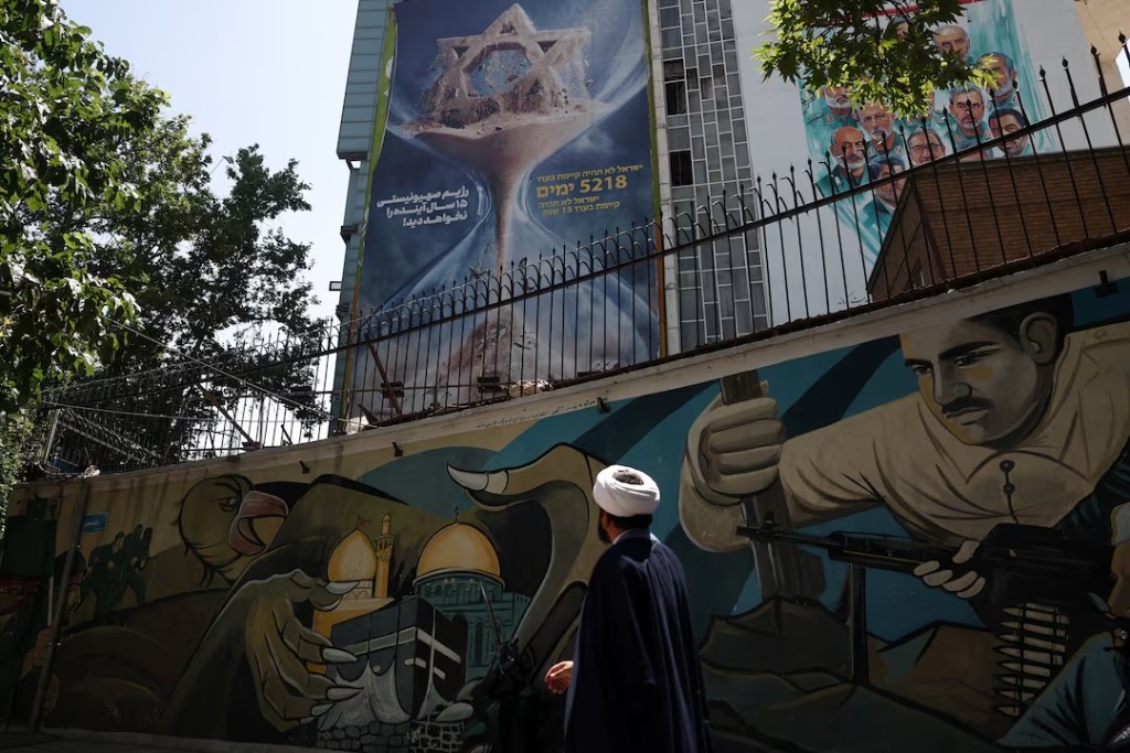An Iranian cleric walks next to an anti-Israeli billboard on a building in Tehran, Iran, June 9, 2026. Majid Asgaripour/WANA (West Asia News Agency) via REUTERS