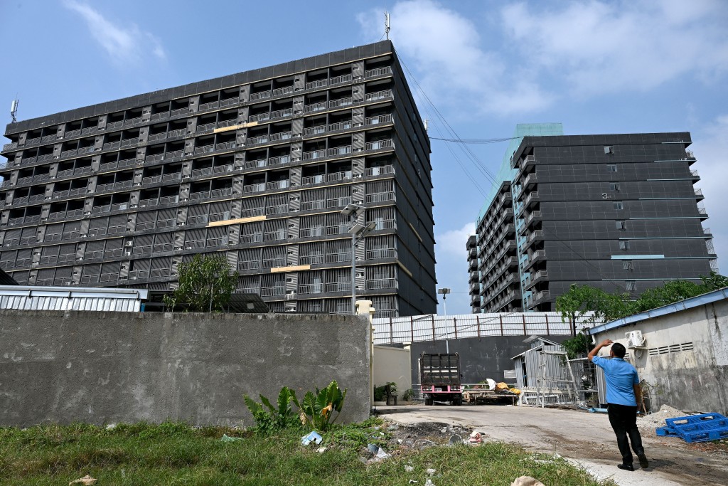 Photo by TANG CHHIN SOTHY / AFP  A man looks at a building known as Jinbei 4, part of a suspected compound built and operated by internationally sanctioned accused scam boss Chen Zhi's Prince Group, in Sihanoukville on January 15, 2026.