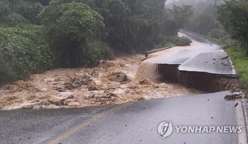 A collapsed road in Chungju, North Chungcheong province, which left one firefighter missing. A collapsed road in Chungju, North Chungcheong province, which left one firefighter missing.