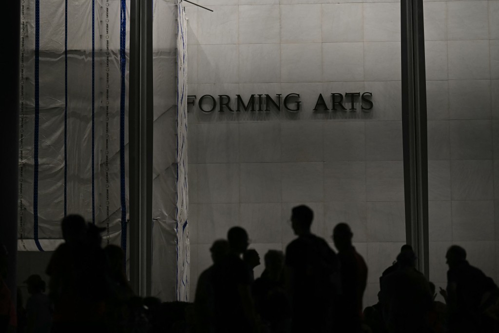 A large tarp covers part of the facade of the Kennedy Center as people linger following a protest in support of the arts center, in Washington, DC, on September 18, 2026. (Photo by Kent NISHIMURA / AFP)