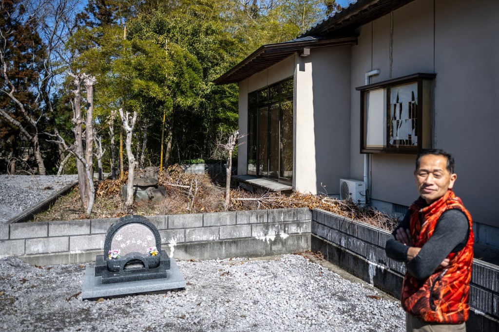 Photo by PHILIP FONG / AFP  This picture taken on March 5, 2026 shows former nuclear plant worker Toru Akama speaking in front of the pets' graveyard at his animal shelter during an interview with AFP, in Namie, Fukushima prefecture.