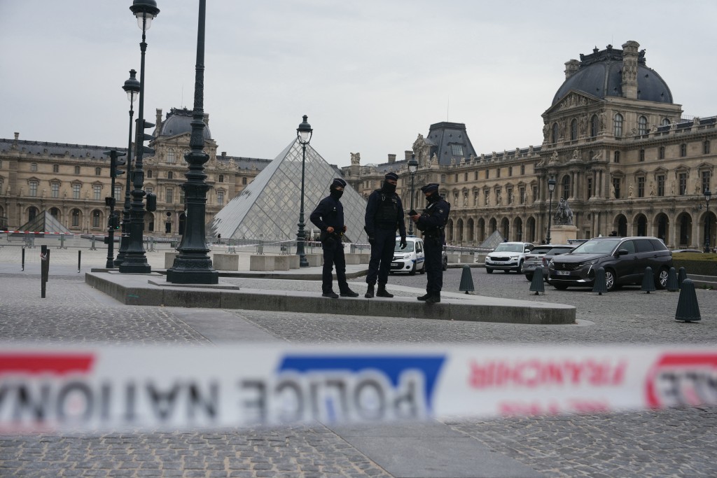 Photo by DIMITAR DILKOFF / AFP.  French police officers patrol in front of the Louvre Museum after it was robbed, with the Louvre Pyramid designed by Ieoh Ming Pei in the background, in Paris on October 19, 2025.
