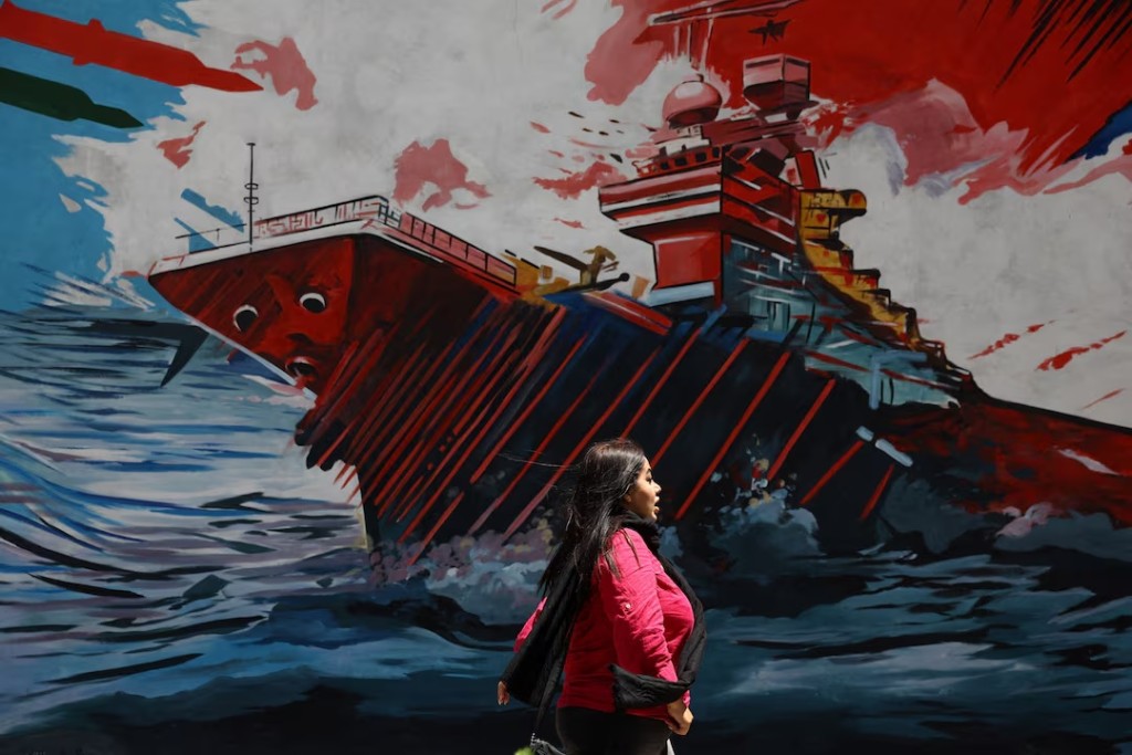 An Iranian woman walks next to a mural on a street in Tehran, Iran, May 6, 2026. Majid Asgaripour/WANA (West Asia News Agency) via REUTERS