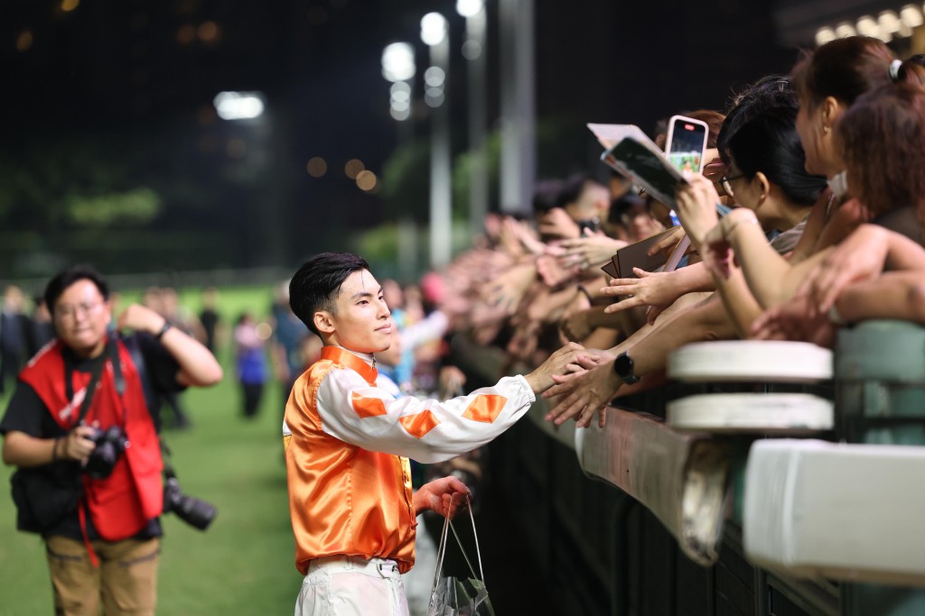 Jockey Ellis Wong Chi-wang gives out souvenirs to spectators. (Sing Tao)