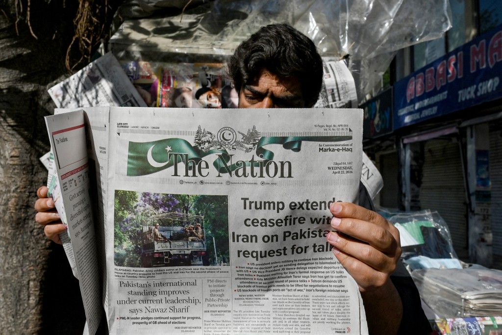 Photo by ASIF HASSAN / AFP  A man reads a newspaper with a front page article referring to anticipated US-Iran peace talks, at a stall in Islamabad on April 22, 2026.
