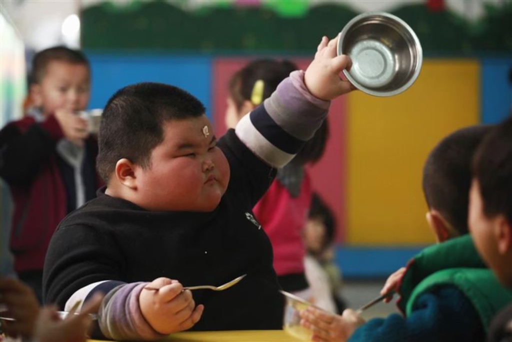 Lu Zhihao, 4, shows his empty rice bowl to his teacher during lunch time at a kindergarten in Foshan, Guangdong province March 29, 2011. REUTERS/Joe Tan