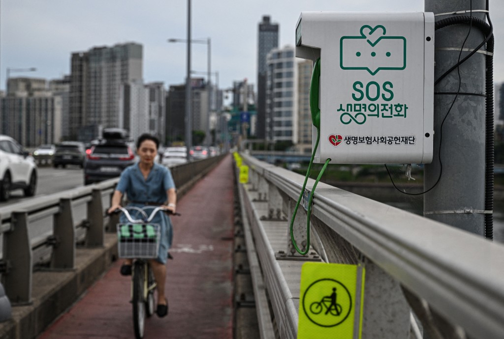 Photo by JADE GAO / AFP. This photo taken on June 24, 2026 shows a suicide-prevention phone installed on a bridge over the Han River in Seoul.