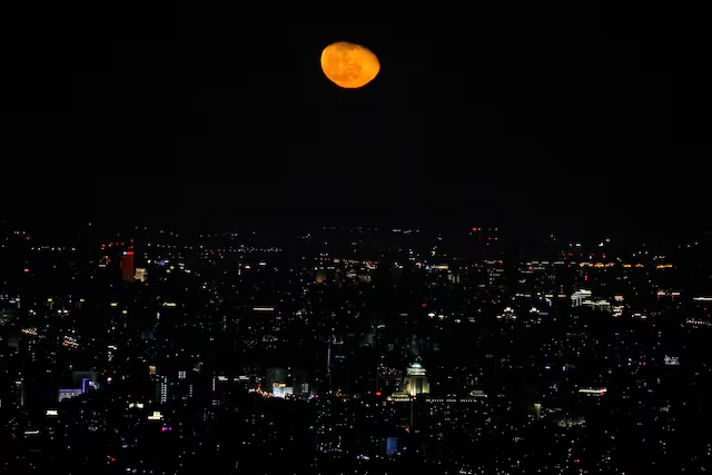 The moon is seen over the city of Beijing, China, February 20, 2022. REUTERS/Tingshu Wang/File Photo 