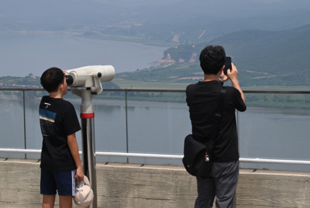 Photo by JUNG YEON-JE / AFP  Visitors use binoculars to watch the North Korean side from a South Korean observation deck at Aegibong Peace Ecopark in Gimpo on July 1, 2026.