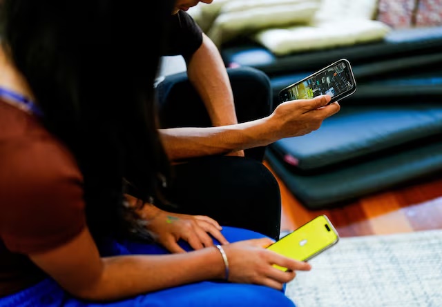Two school students pose with their mobile showing social media applications in Melbourne, Australia, November 28, 2024. REUTERS/Asanka Brendon Ratnayake/File Photo