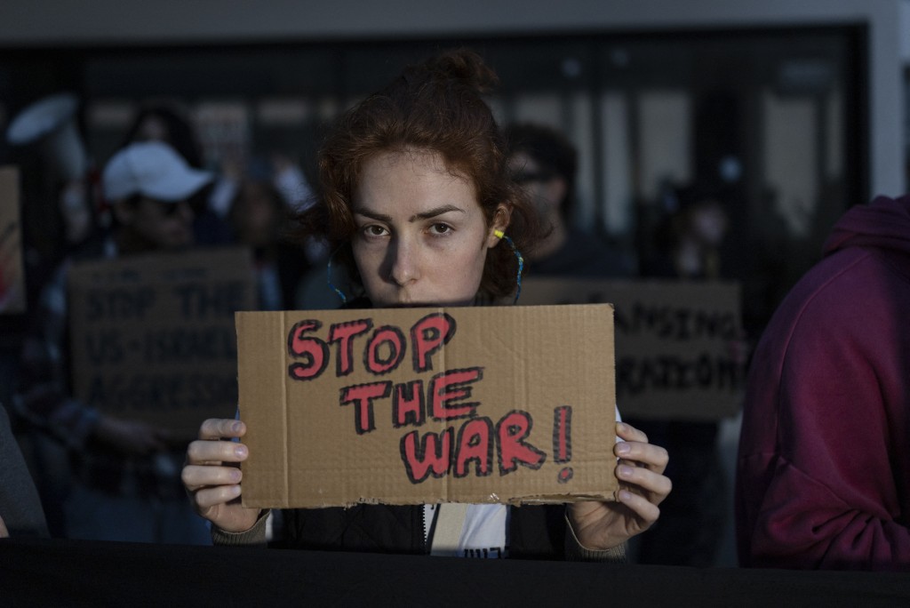 Photo by ILIA YEFIMOVICH / AFP  Israeli left-wing activists hold placards during a protest outside the US Embassy in Tel Aviv on April 6, 2026, against the ongoing war with Iran.