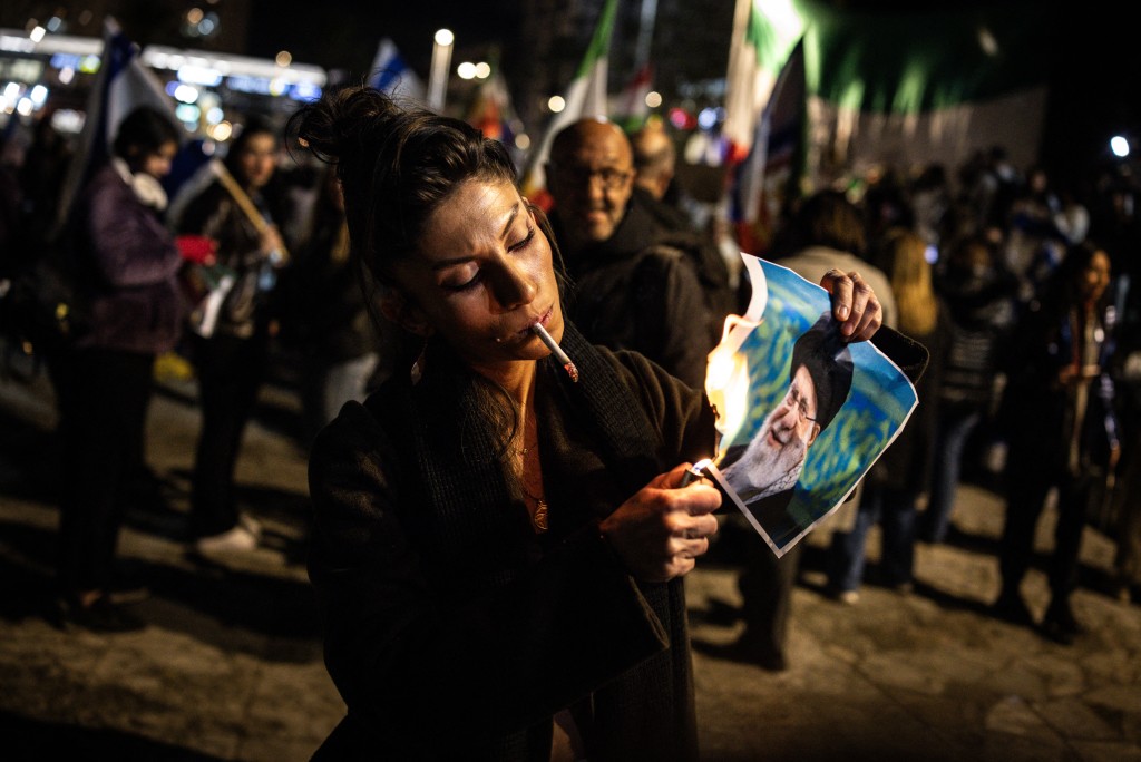 Photo by JOHN WESSELS / AFP  A woman burns a portrait of Iran's Supreme Leader, Ayatollah Ali Khamenei after lighting a cigarette during a demonstration in solidarity with Iranian protestors, in Israel's central city of Holon on January 14, 2026.