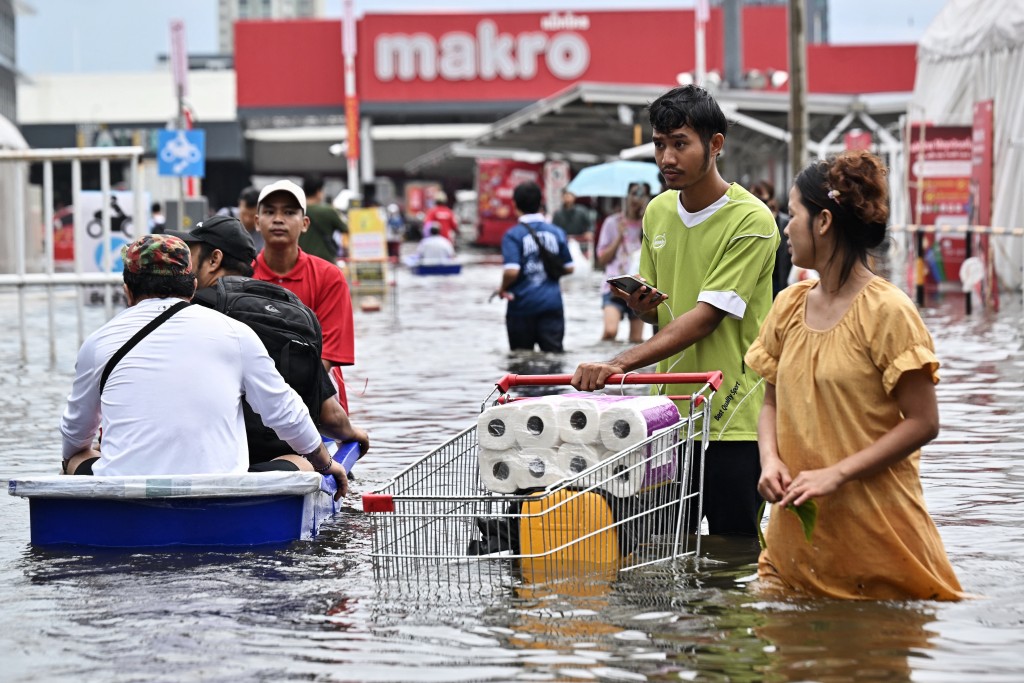 Residents leave Makro supermarket while navigating floodwater in Bang Kapi district in Bangkok on September 28, 2026. (AFP)