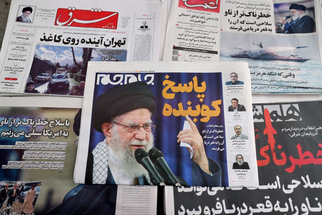 Photo by ATTA KENARE / AFP  Daily Iranian newspapers are fronted with the image of Iran's Supreme Leader Ayatollah Ali Khamenei and other headlines, displayed at a kiosk in Tehran on February 18, 2026.