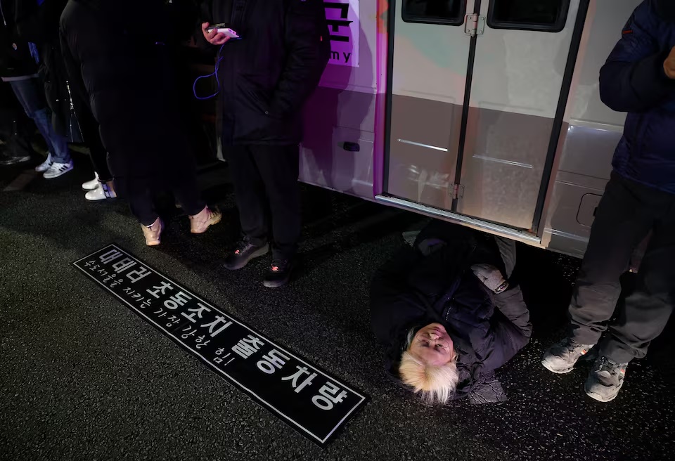 A woman lies on a road to block a vehicle transporting an army unit, after South Korean President Yoon Suk Yeol declared martial law, in Seoul, South Korea. (AP)