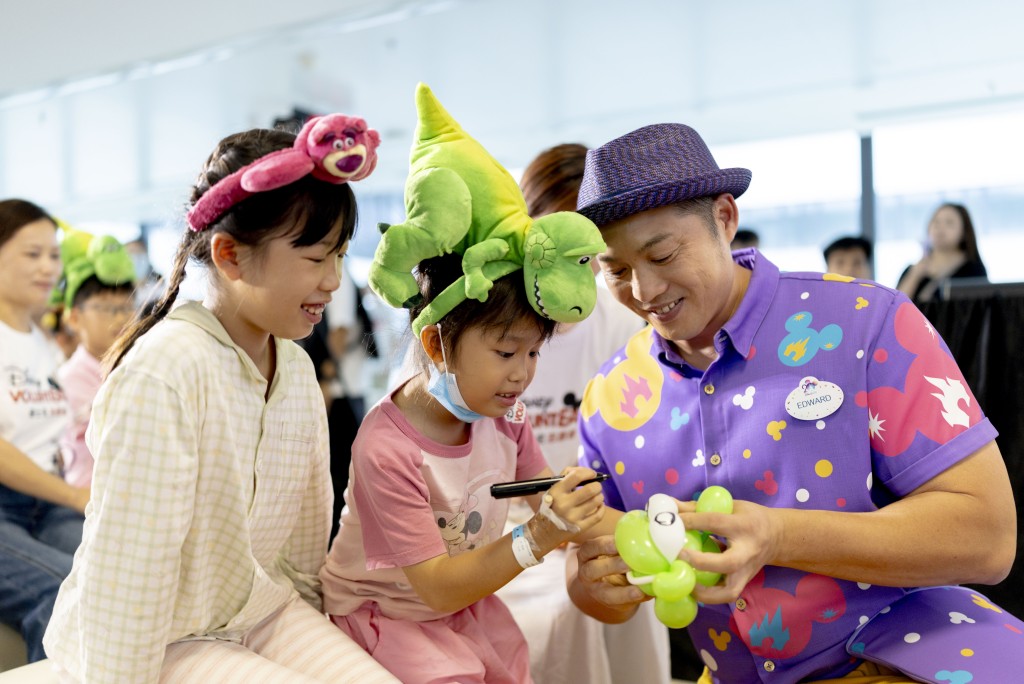 A Disney balloon artist crafts an alien balloon bracelet for Xiao Xian.