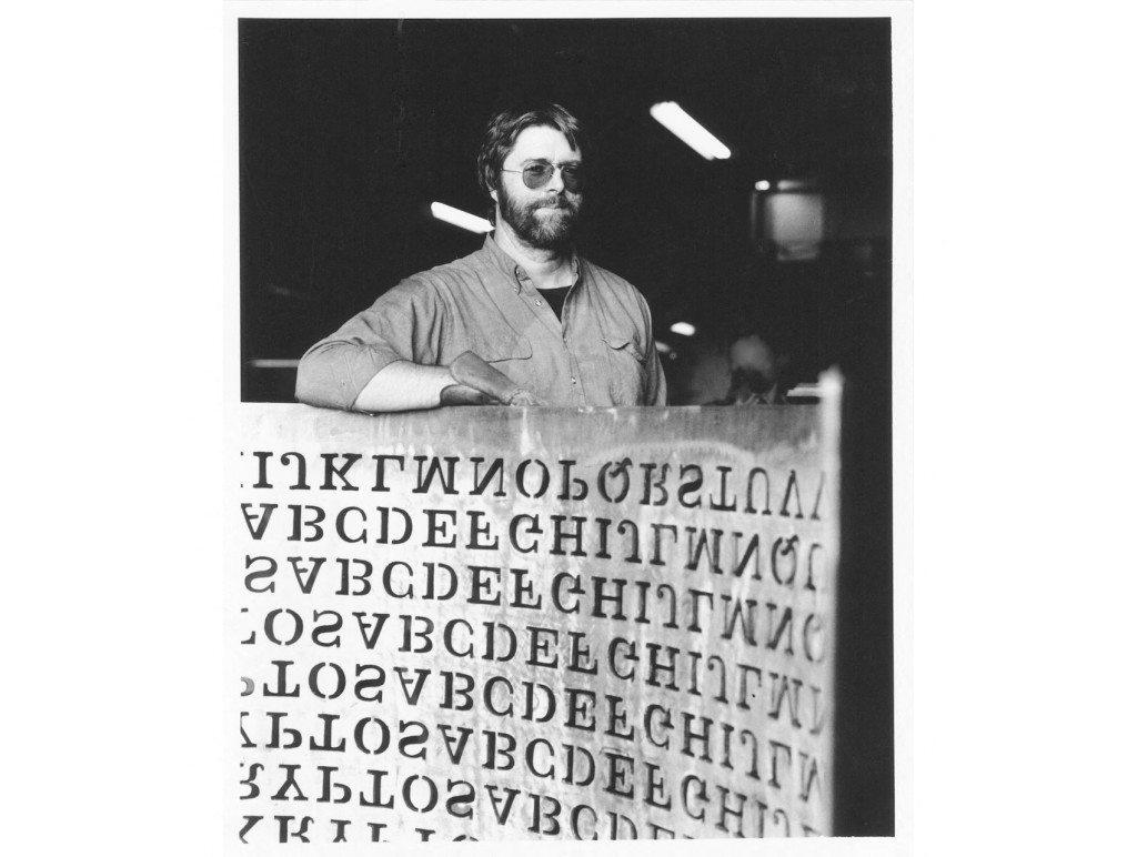 Photo by HANDOUT / COURTESY OF JIM SANBORN / AFP  This 1990 handout photo, courtesy of Jim Sanborn, shows sculptor Jim Sanborn with a cut of his "Kryptos" copper sculpture.