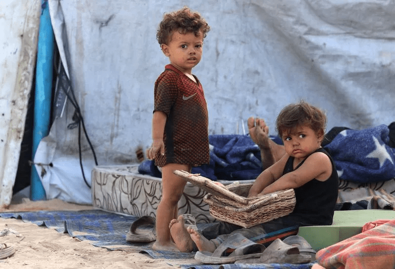 Displaced Palestinian children shelter on the side of a raod, after Hamas agreed to release hostages and accept some other terms in a U.S. plan to end the war, in the central Gaza Strip, October 4, 2025. REUTERS/Dawoud Abu Alkas